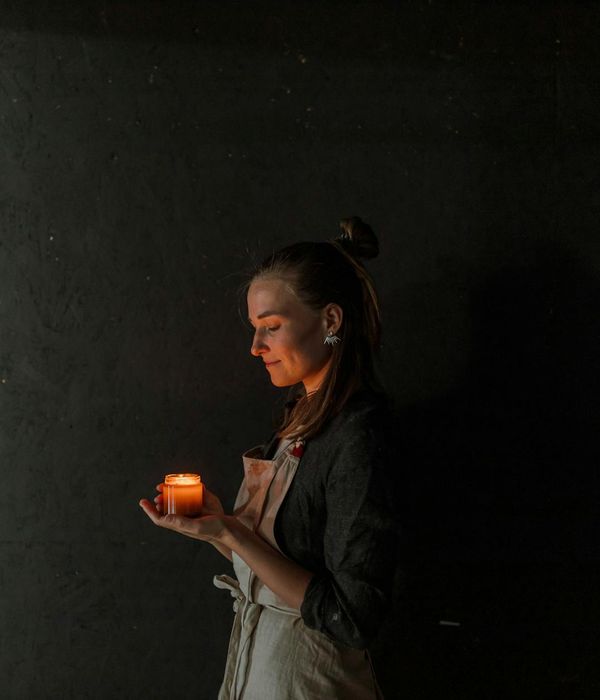 Woman in a calm, meditative pose in a softly lit room.
